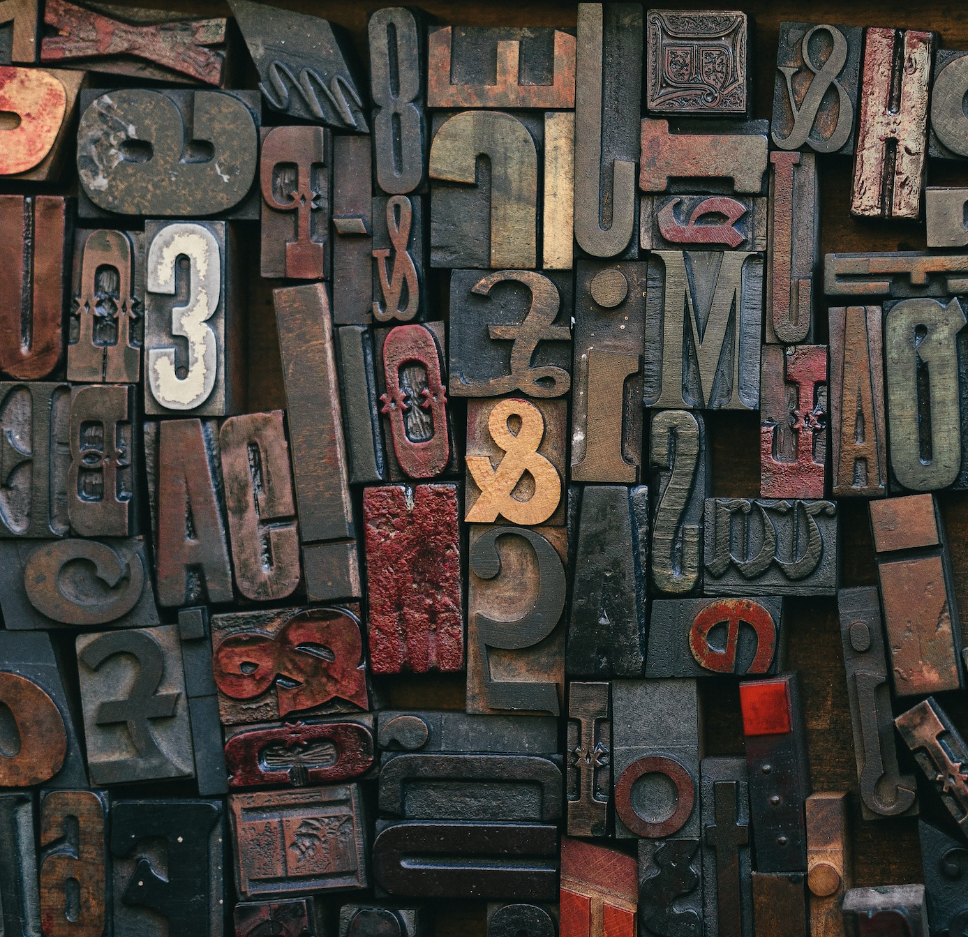A collection of wooden letters loosely arranged. The letters are used for stamps.